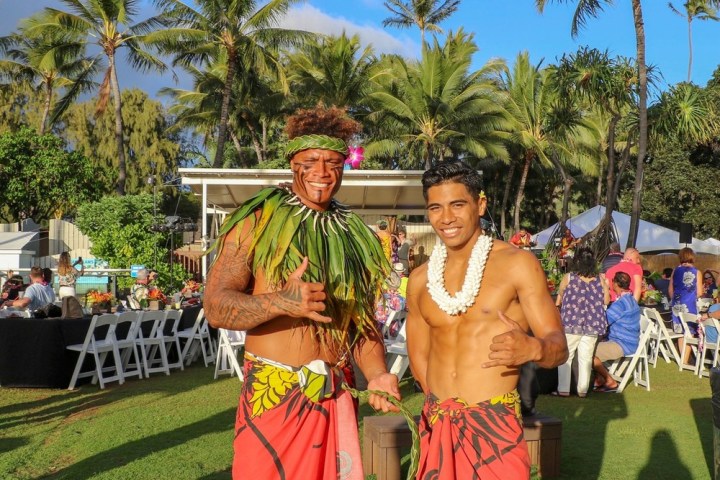 a group of people standing next to a palm tree
